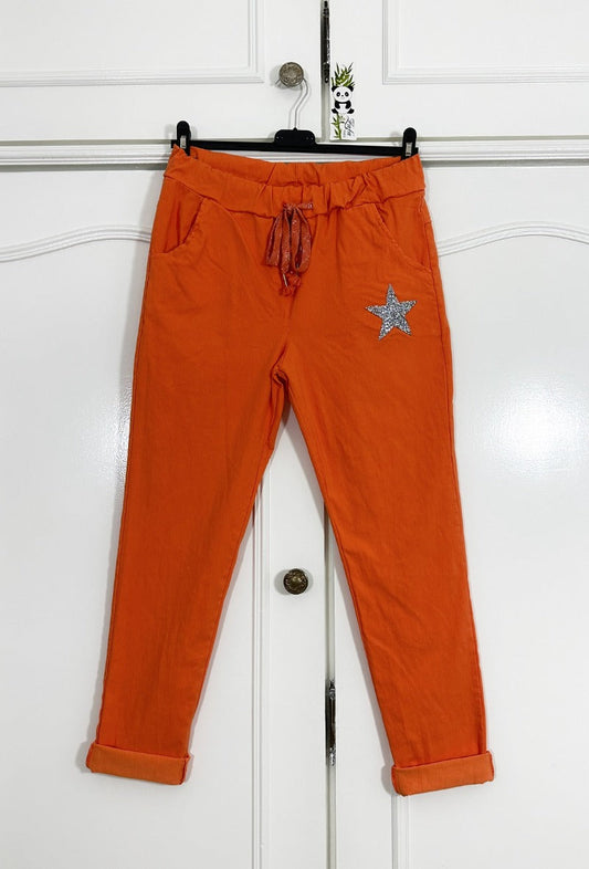 Pantalon uni orange avec poche sur les côtés et patch étoile